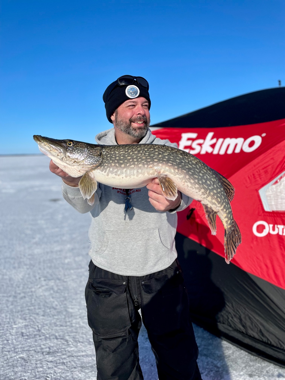 Jarred holding a big northern pike in front of an Eskimo ice shelter